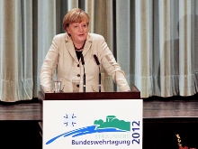 Merkel vor Rednerpult - Link zum Bericht