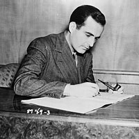 Samuel Barber, seated, making notes on his music