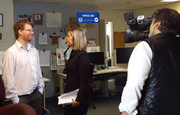 Figure 1. Franco Villela (left), Brazilian student at the HPC International Desks, was interviewed by TV Globo Brazil's Chief Weathercaster Flavia Freira (center), while cameraman Orlando Moreira da Silva (right) recorded the action.
