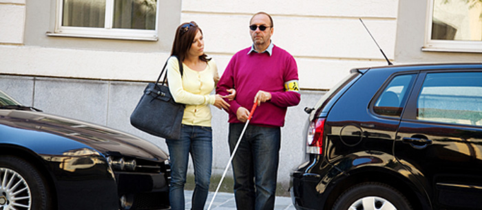 woman and blind man crossing street