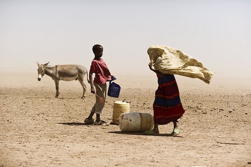 A boy and a woman struggle with dusty wind looking for water in Wajir, Kenya