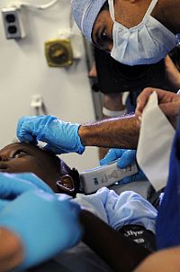 Dr. Sanjay Gupta, a CNN medical correspondent and practicing neurosurgeon, prepares a 12-year-old Haitian girl with a severe head injury for surgery aboard the Nimitz-class aircraft carrier USS Carl Vinson (CVN 70).