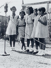 Four Mexican girls singing into a microphone