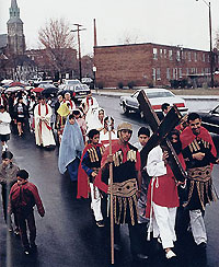 Street procession: parishioners in costume portray Roman soldiers escorting Jesus who is bearing a cross.