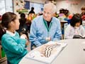 AARP Experience Corps tutor Fred Brundage assists third graders Amy Chang, left, and Thiri Than with their reading skills.