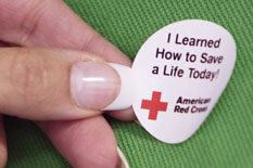 Woman placing "I learned how to save a life today" sticker on someone.