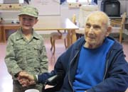 Photo of eight year old Evan Green shaking hands with World War II Veteran Felix Wilczynski.