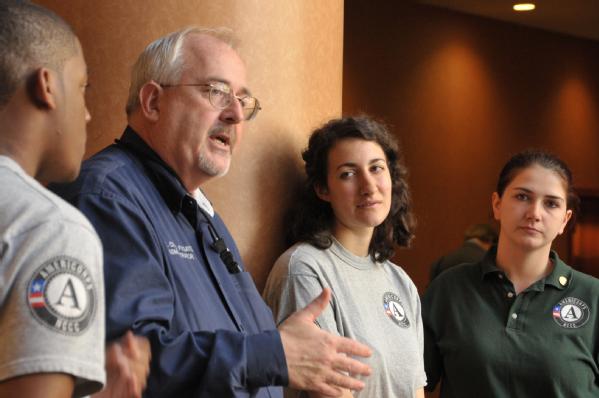 FEMA Administrator Craig Fugate speaks while flanked by two FEMA Corps members.