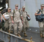 Photo of a group of male service members walking off a ship, returning home.