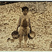 Manuel, the young shrimp-picker, five years old, and a mountain of child-labor oyster shells behind him. He worked last year. Understands not a word of English. Dunbar, Lopez, Dukate Company.  Location: Biloxi, Mississippi. (LOC)