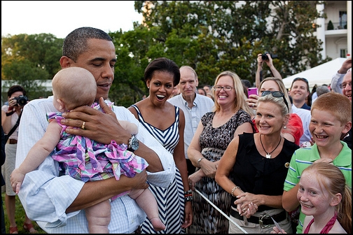 First Lady Michelle Obama reacts as President Barack Obama soothes a crying baby
