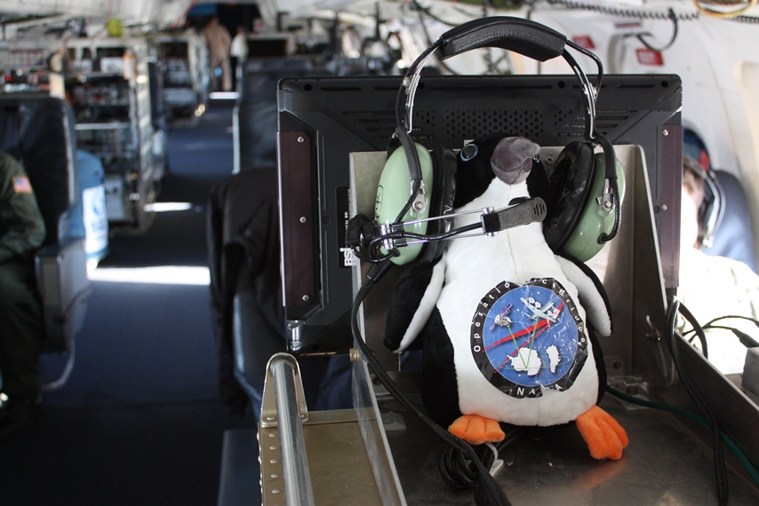 The IceBridge penguin mascot using the DC-8's satellite phone headset.