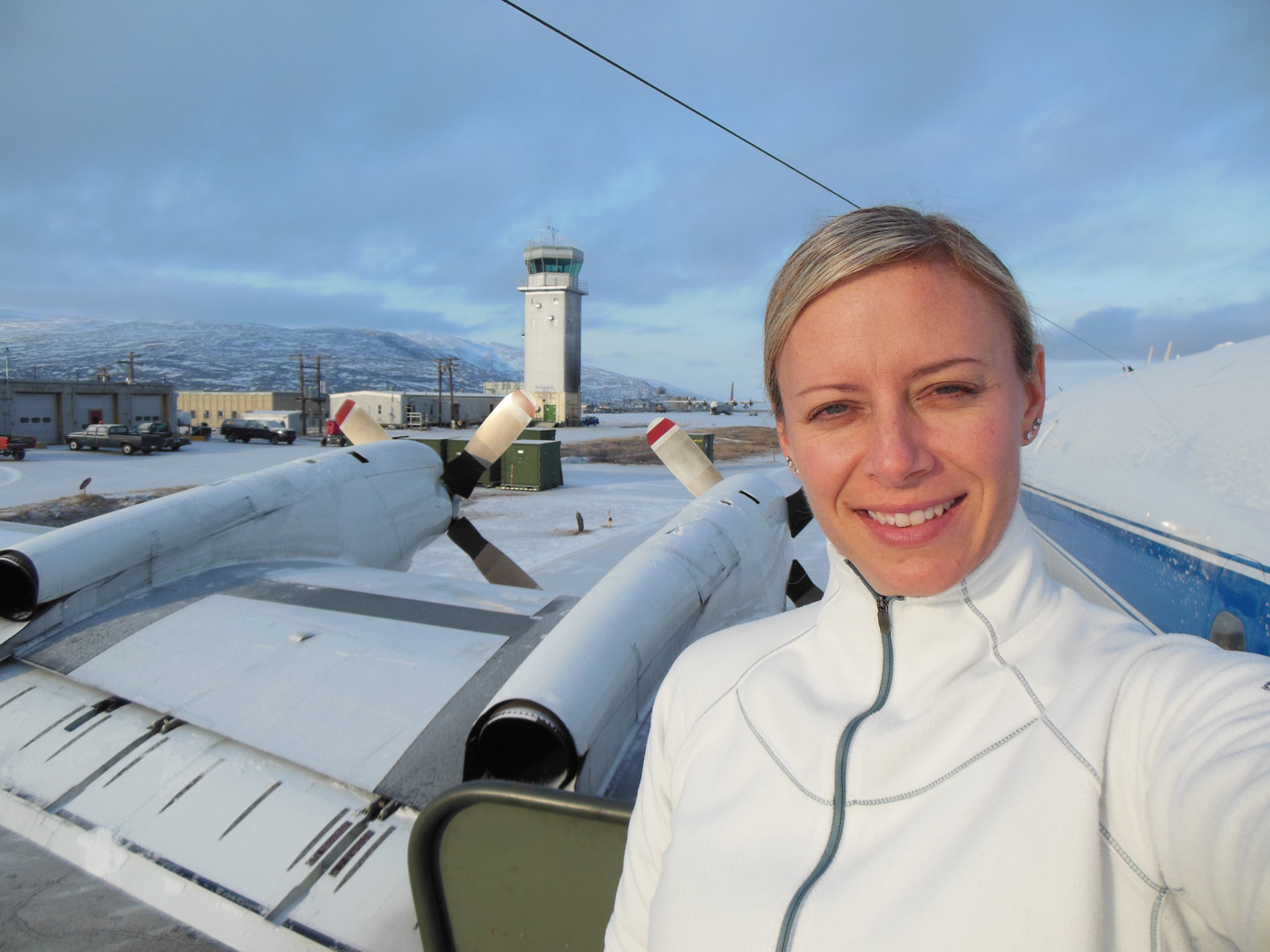 Christy Hansen in Kanger, Greenland, after one of Operation IceBridge’s science flights. Behind her is the air traffic control tower, as well as the P-3B propellers.