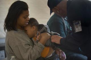 Photo: (Nov. 11 2012) Dr. David Levine, assigned to Natural Disaster Medical System, checks the vital signs of resident Deshawn Thomas, son of Tiffany Belcher, at a Disaster Assistance Medical Team location in Queens, N.Y. In response to Hurricane Sandy, the Natural Disaster Medical System team and U.S. Army National Guard deployed a Disaster Assistance Medical Team to Queens, N.Y. to assist residents with medical issues.  (Photo by Mass Communication Specialist 3rd Class Patrick Ratcliff USN/Released) Digital