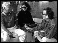 Two men and a woman laughing while in a boat.