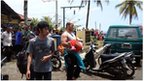 In this handout photograph released by Pikiran Rakyat, an unidentified survivor carrying a child is escorted at a marine police station on the coast of Pangandaran town in Indonesia's West Java province on November 1