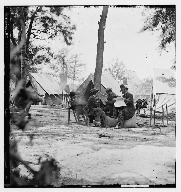 [Gen. Ambrose E. Burnside (reading newspaper) with Mathew B. Brady (nearest tree) at Army of the Potomac headquarters] (LOC)