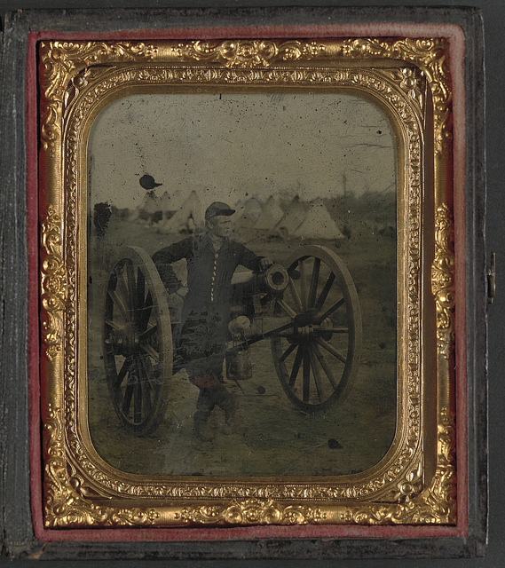 [Unidentified soldier standing with Napoleon cannon in front of encampment] (LOC)