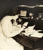 A woman seated at a desk, talking on the telephone.