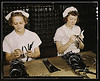 Two Navy wives, Eva Herzberg and Elve Burnham, entered war work after their husbands joined the service, Glenview, Ill. They assemble bands for blood transfusion bottles at Baxter Laboratories. Mrs. Burnham is the mother of two children (LOC) by The Library of Congress