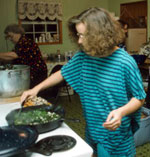 A woman at a stove, stirring the vegetables in a skillet.
