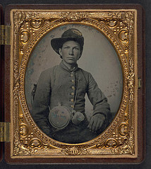 [Unidentified young soldier in Confederate shell jacket, Hardee hat with Mounted Rifles insignia and plume with canteen and cup] (LOC)