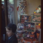 Boy beside store window display of Christmas ornaments