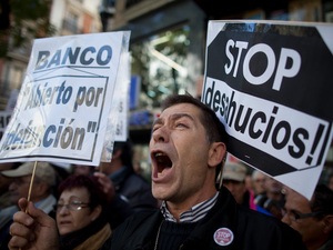 A demonstrator shouts during a protest against housing evictions in Madrid last month. The sign to his right reads, "Stop evictions."