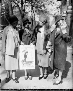 Mrs. John J. Mitchell, Jr. and three other women, one holding a sign for a fashion show