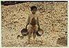 Manuel, the young shrimp-picker, five years old, and a mountain of child-labor oyster shells behind him. He worked last year. Understands not a word of English. Dunbar, Lopez, Dukate Company.  Location: Biloxi, Mississippi. (LOC) by The Library of Congress