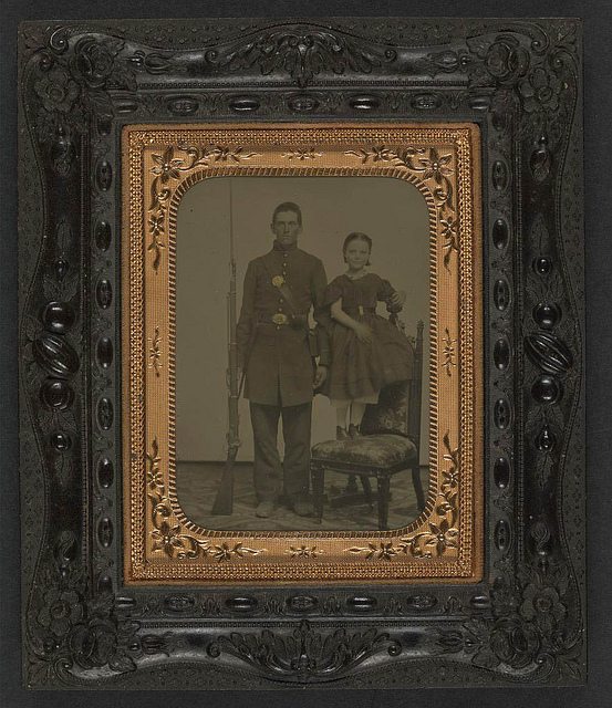 [Unidentified young soldier in Union frock coat with bayoneted musket next to unidentified young girl standing on chair; probably siblings] (LOC)