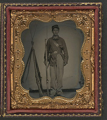[Unidentified young soldier in Union uniform with bayoneted musket next to a rifle stack] (LOC)