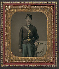 [Unidentified young soldier in Union uniform next to chair draped with overcoat] (LOC)