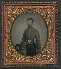 [Unidentified soldier in Union cavalry uniform with cavalry saber next to table with Cavalry Company D Hardee hat] (LOC)