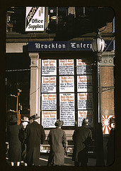 Men and a woman reading headlines posted in street-corner window of Brockton Enterprise newspaper office on Christmas Eve, Brockton, Mass. (LOC)