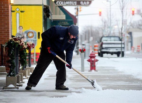 Phillip Forney shovels snow and ice in downtown Columbus, Ind.