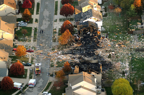 Debris litters an Indianapolis neighborhood the day after a blast leveled two homes and damaged many more.
