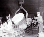 A worker pouring hot metal into a kiln