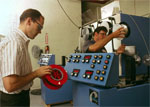 Two men working with an electronic machine