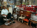 McDowell sitting in a barber's chair in his barber shop