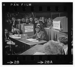 Photograph shows Henry seated at a table reading from a document