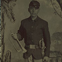Young soldier in Union uniform and infantry forage cap with sheathed musicans' sword and bugle