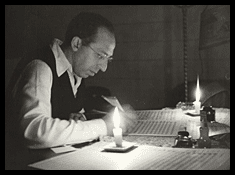 Aaron Copland at his desk by candlelight
