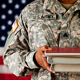Soldier holding books in front of the American flag