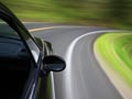 AARP volunteers help teach driver safety programs for members- a car driving speedily around a curve on a road