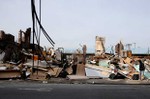 A man walks past a small commercial strip that burned down during Superstorm Sandy in the Rockaways section of New York, Wednesday, Jan. 2, 2013. 
