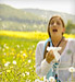 Woman sneezing with tissue in meadow