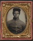 [Unidentified African American soldier in Union cavalry uniform with cavalry saber in front of painted backdrop showing landscape]