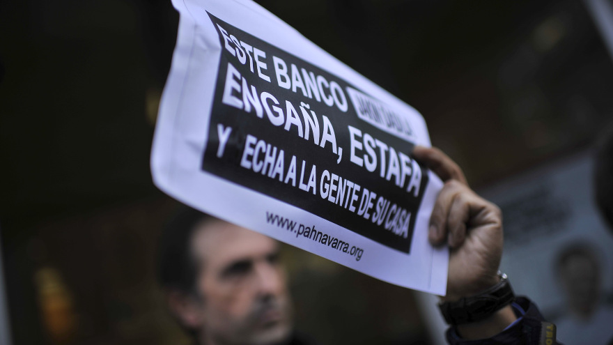 A Spanish protester holds up a sign criticizing a bank