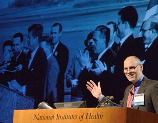 NICHD director Dr. Alan Guttmacher gestures toward a slide showing President John F. Kennedy on Oct. 17, 1962, the day JFK signed legistation creating the child health institute.